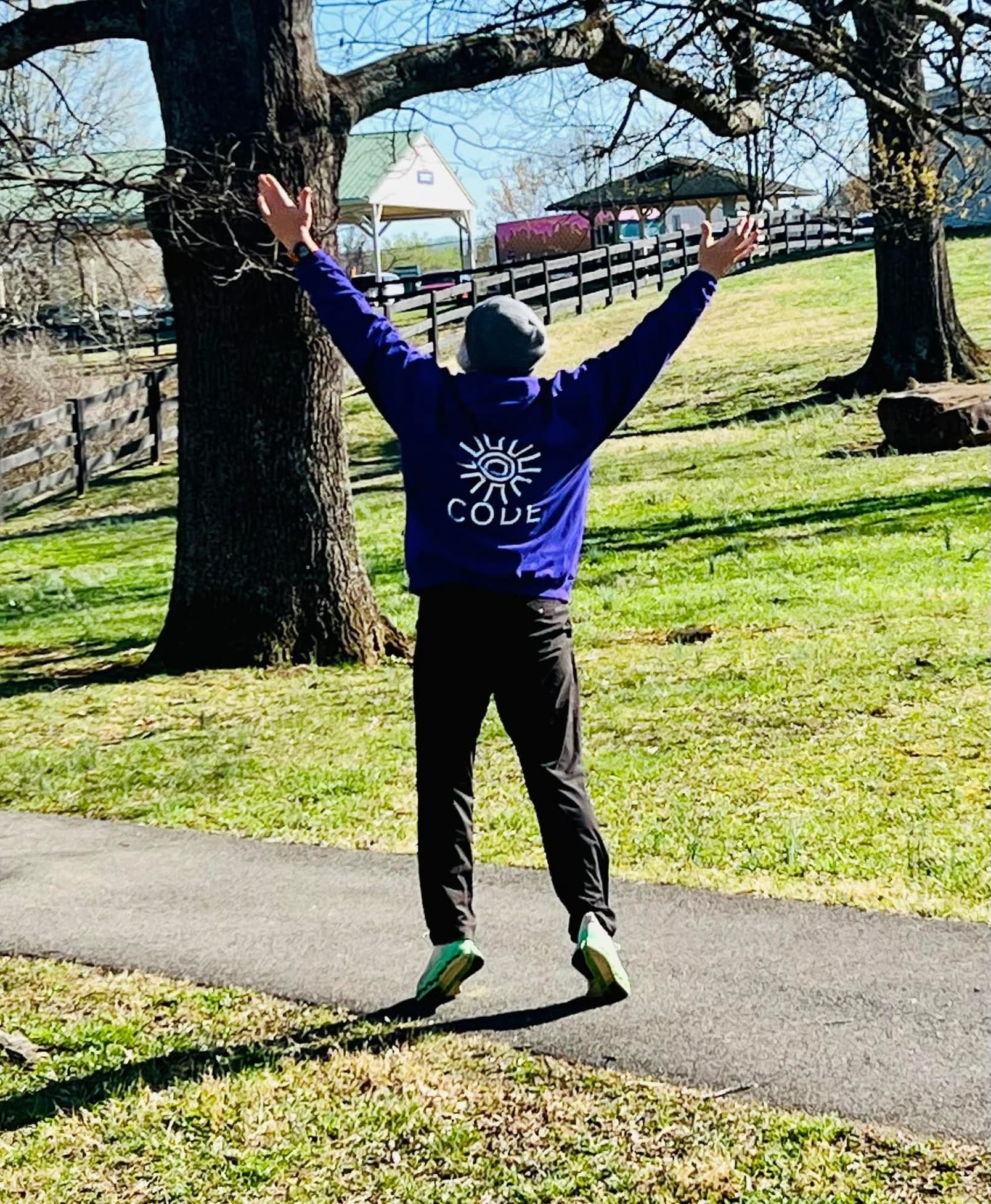 Person in CODE hoodie arms raised in park